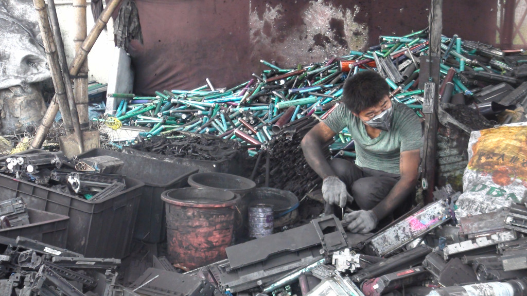 Laborer dismantling toner cartridges. Guiyu, China