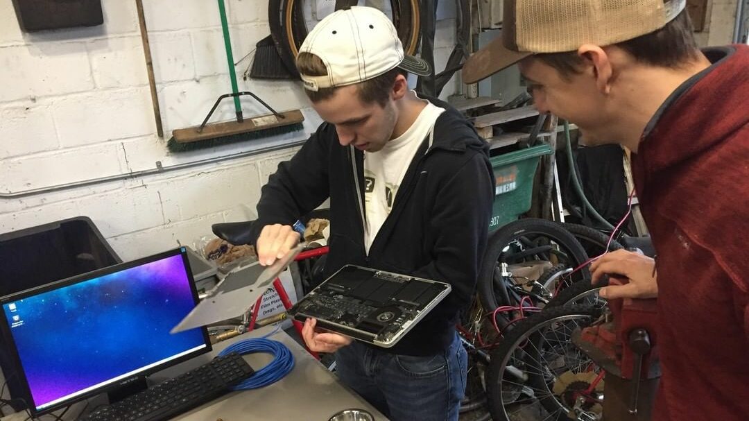 two people work on repairing a laptop