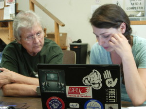 two people work at a laptop with colorful stickers